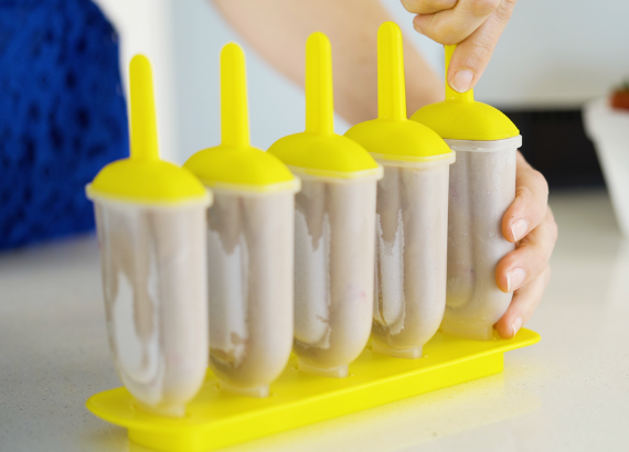 Hand reaching to pull a popsicle out of a popsicle mold